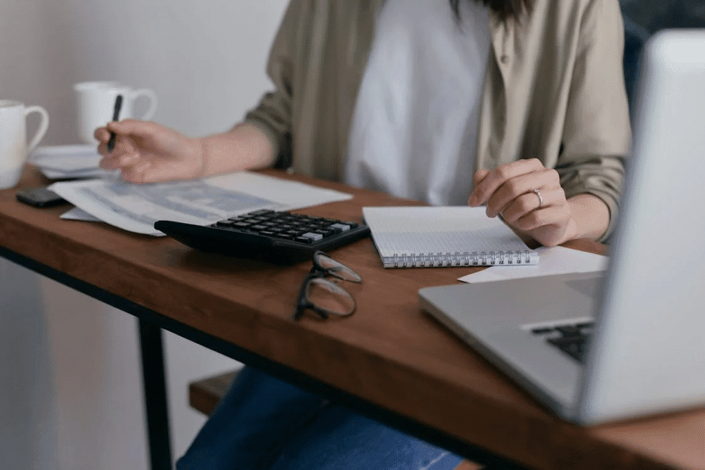 A woman working on a desk with a calculator, documents, etc